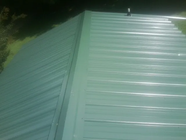 New green metal panels meeting at the ridge of a roof — Flat Roof Repair work by our crew in New Laguna