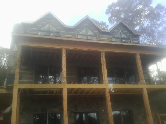 Dormers and porch framing on a large log home under construction — Roof Coating work by our crew in New Laguna