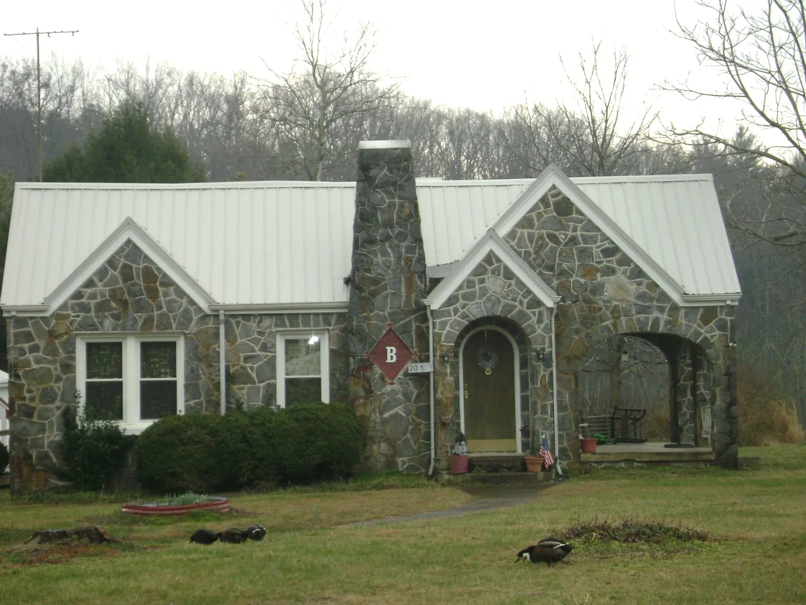 White metal roof on a stone cottage with steep gables in New Laguna
