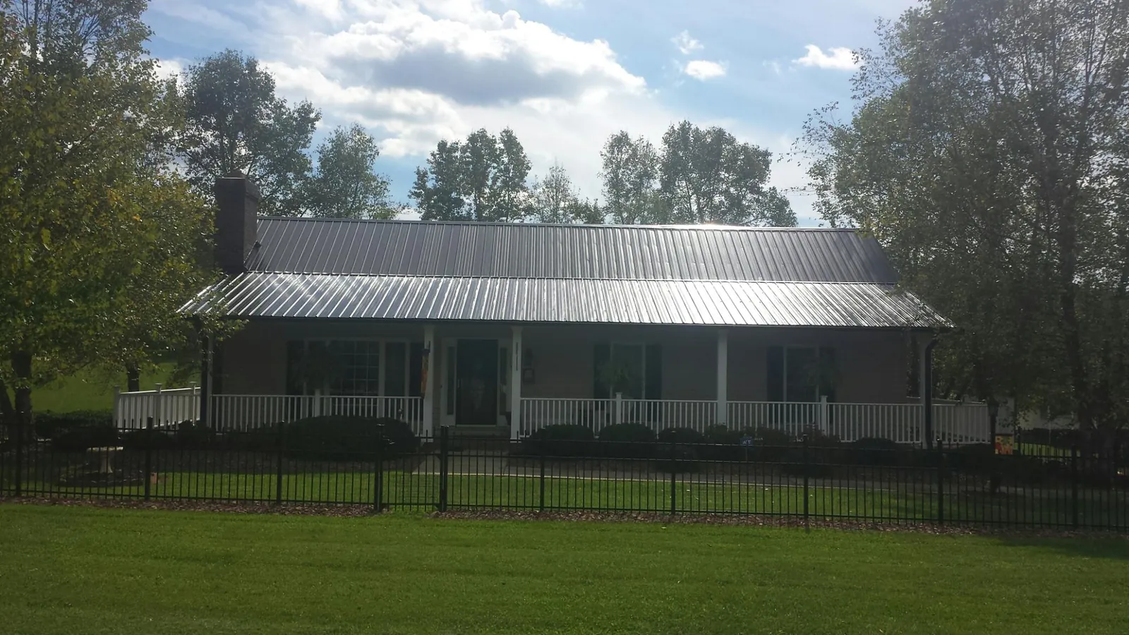 Gray metal roof on a brick ranch with a full width front porch — Gutter Guard Installation work by our crew in New Laguna
