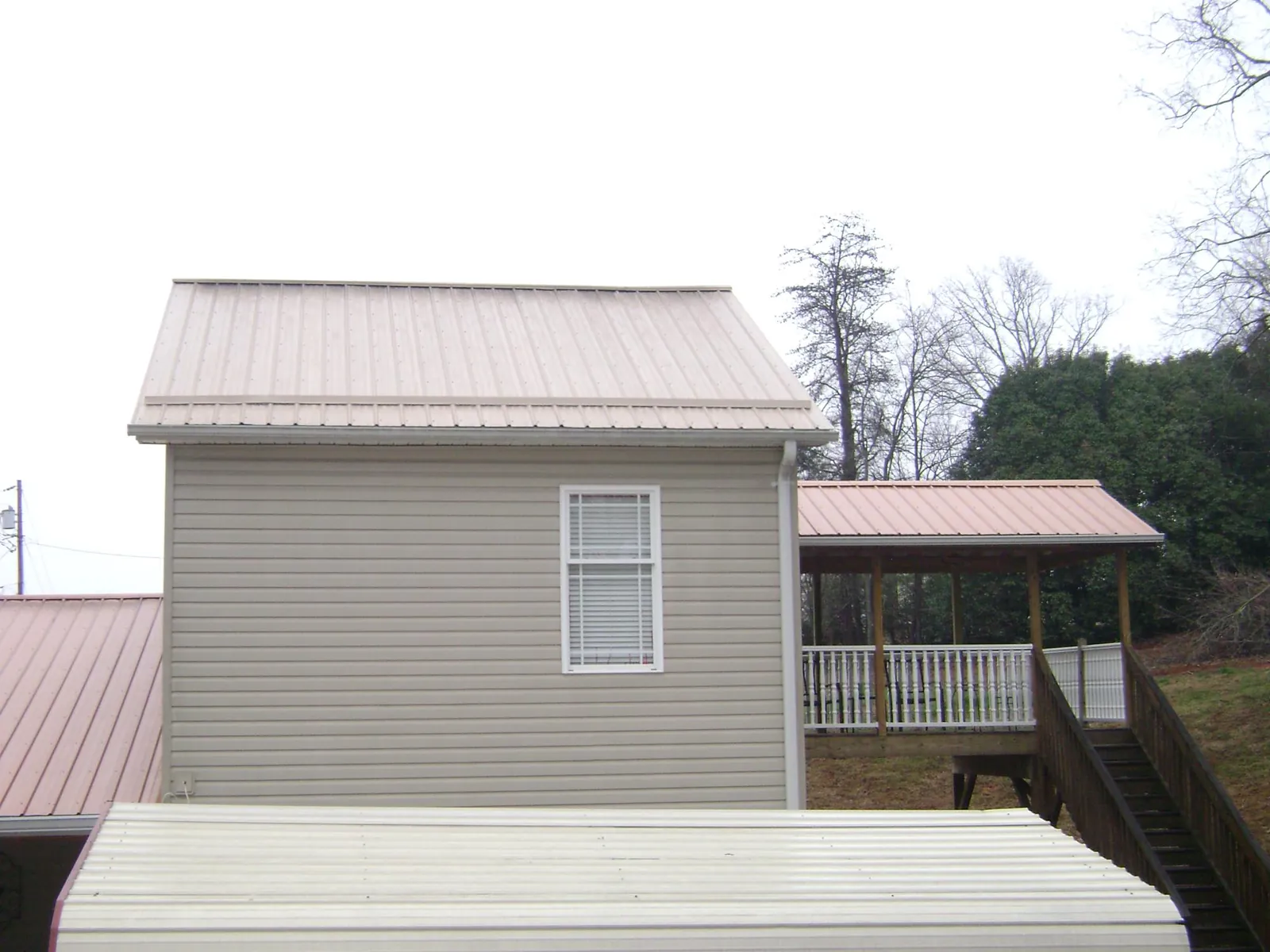Tan metal roofs on a two story addition and attached porch, from a Roof Replacement job in New Laguna
