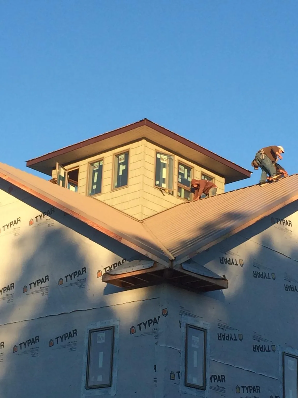 Roofers working around a rooftop cupola on a new metal roof at sunset — Roof Waterproofing in New Laguna by Roofing Brothers